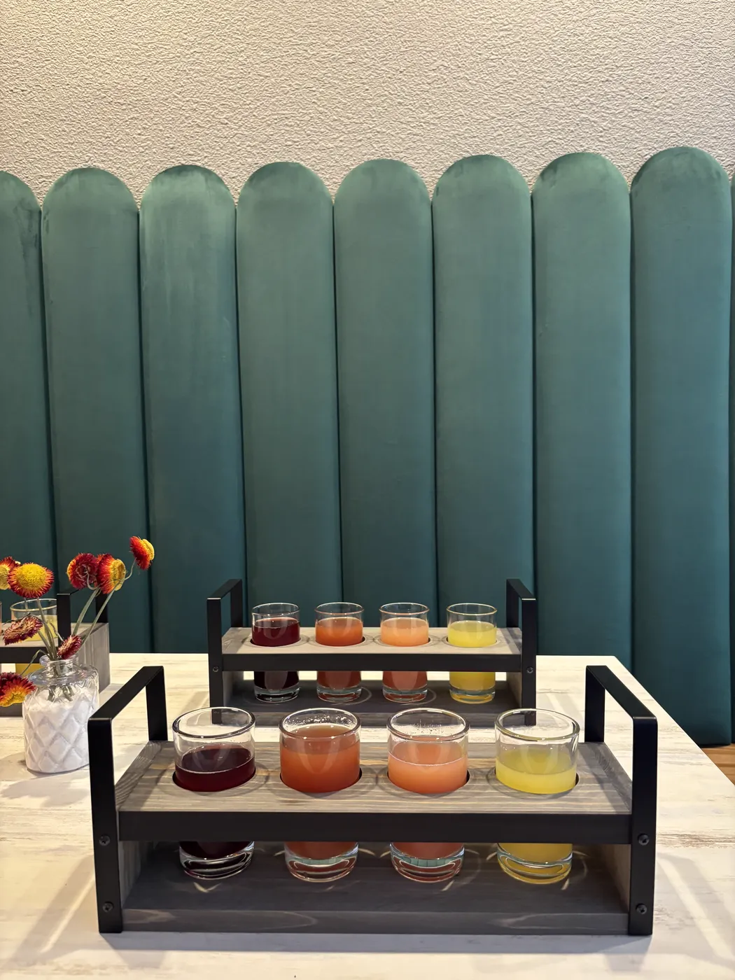 Two mimosa flights in wooden carriers in front of the green booth